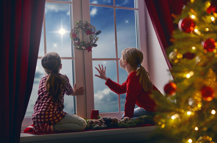 Children looking at star with Christmas tree in the background | Is it wrong to celebrate Christmas