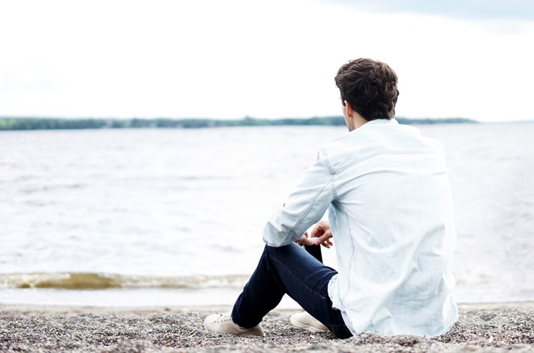 Man sitting by water, reflecting - Can true Christians have addictions?