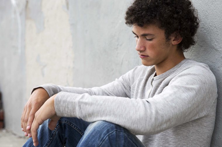 Young man with back to wall, feeling guilty over sin