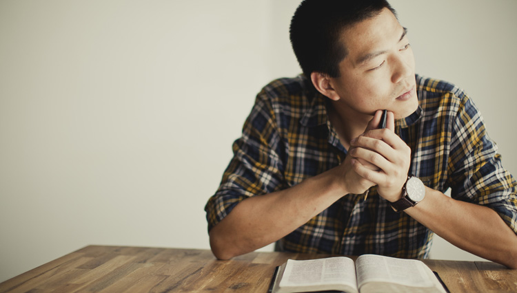 Man reading Bible thinking - Is God a racist?