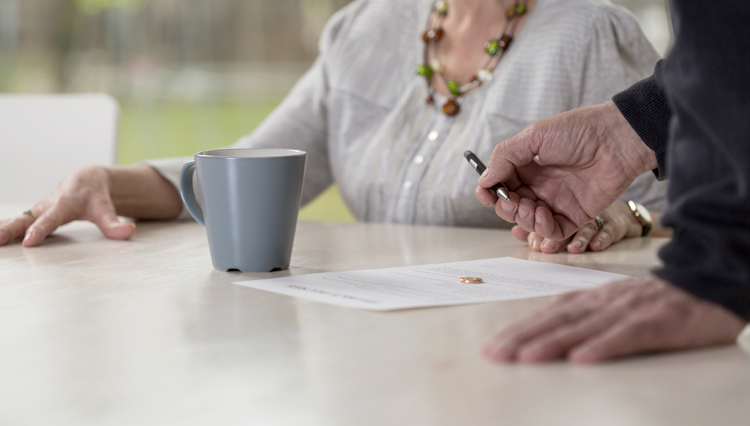 Picture of man signing divorce paper with wife