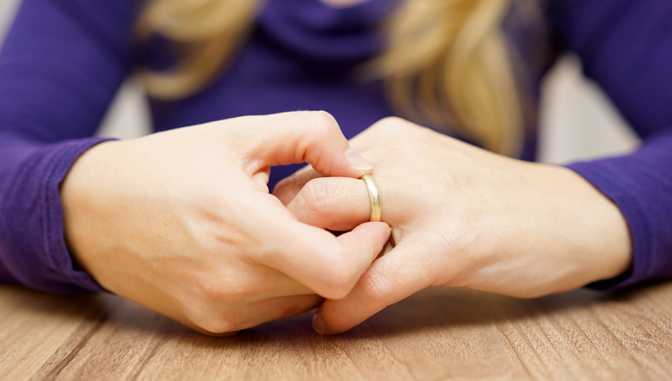 Picture of woman taking wedding ring off finger - symbolic of divorce