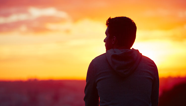 Picture of man looking at sunset, reflecting on motives