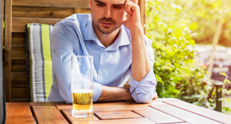 Man looking at glass of alcohol